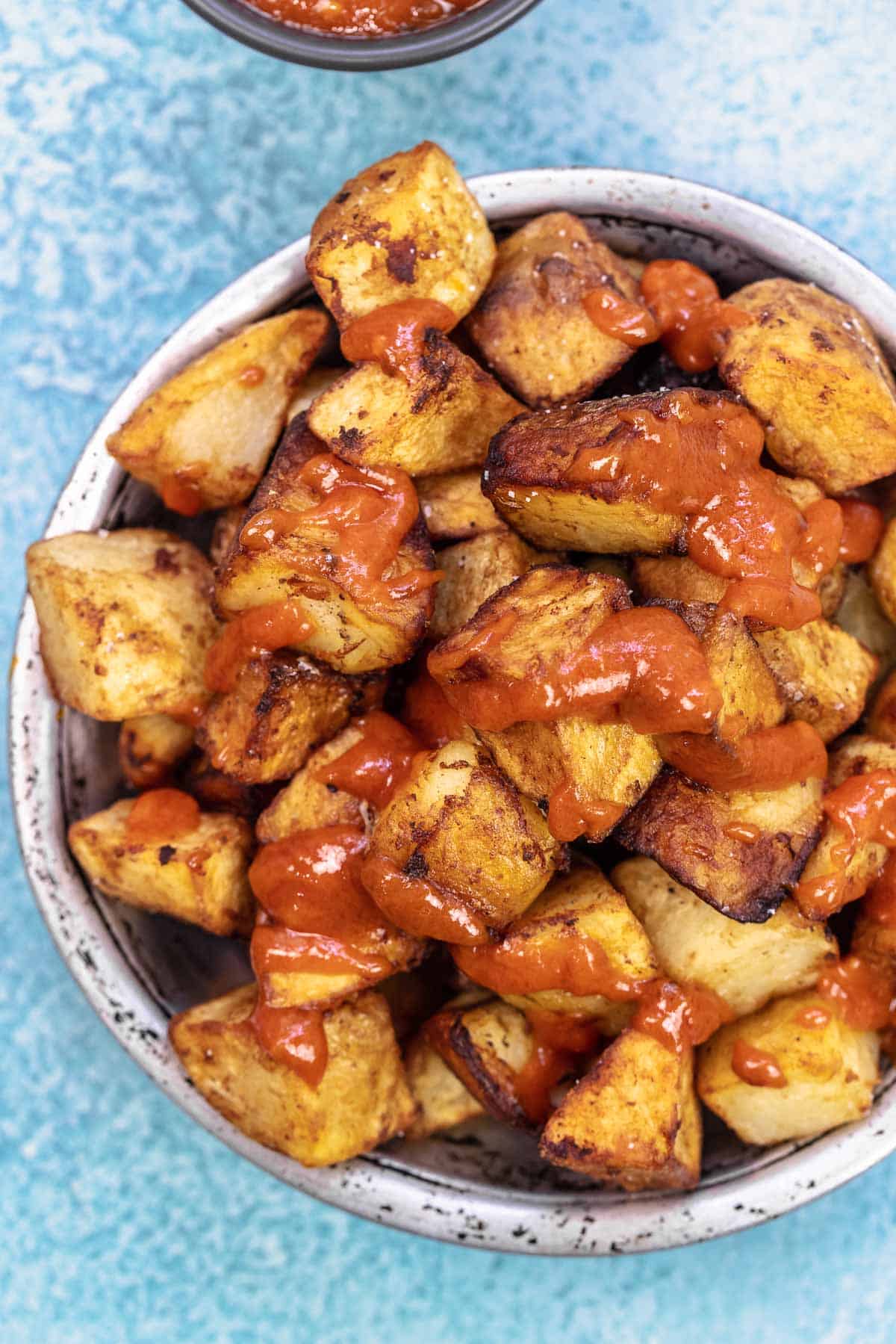 patatas bravas in a bowl with salsa brava drizzled on top.