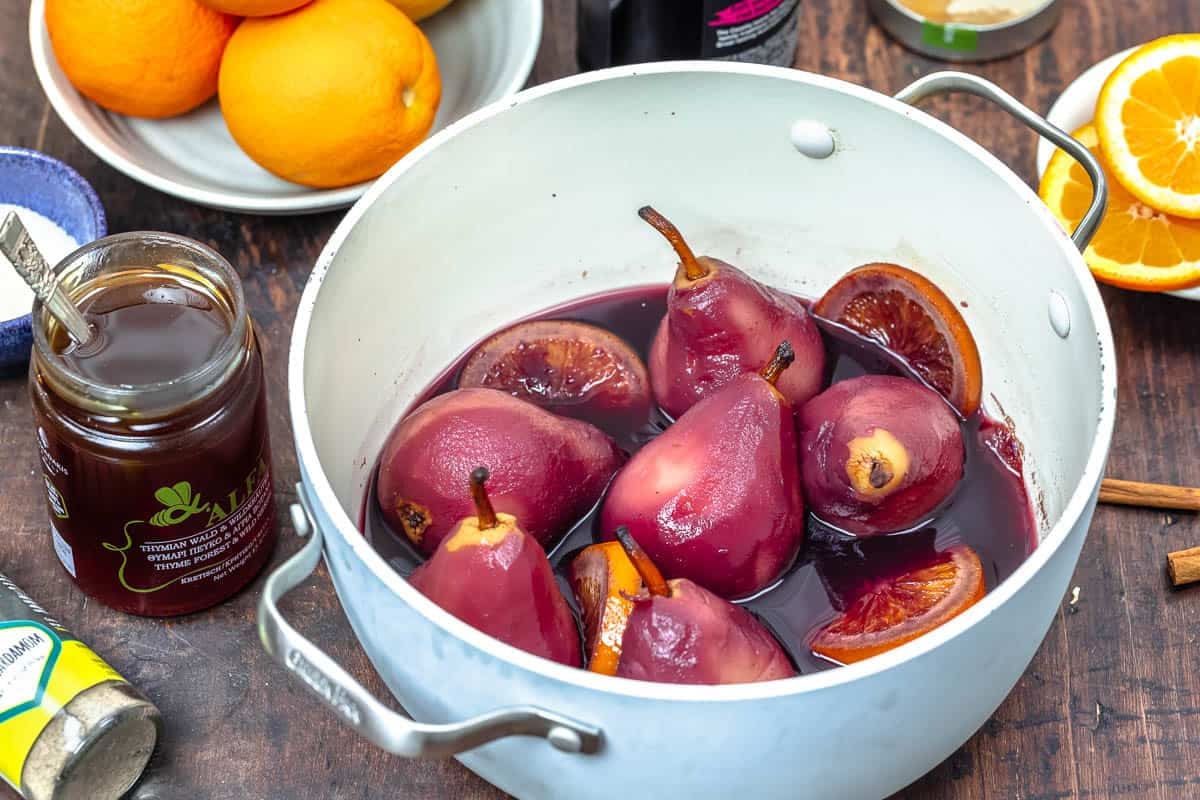 pears in a pot with red wine and spices.