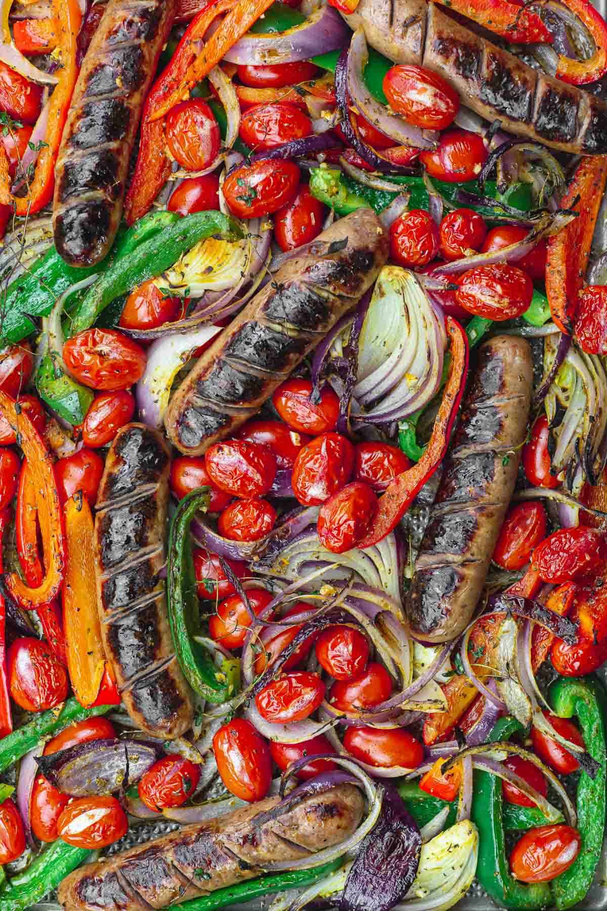 charred sausage and vegetables on a sheet pan.