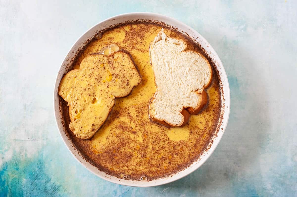 slices of french toast being dipped in custard.