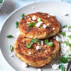 two potato pancakes with feta cheese and a fork on a plate.