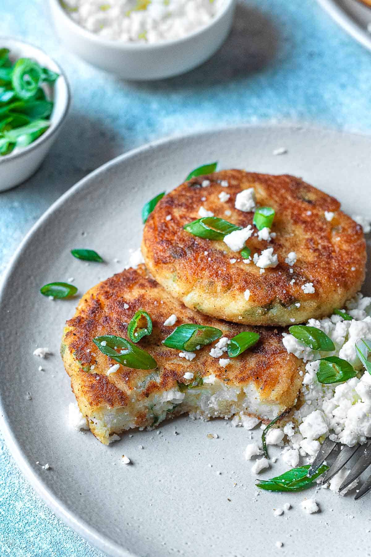 A plate with mashed potato pancakes with a bite taken out of one.