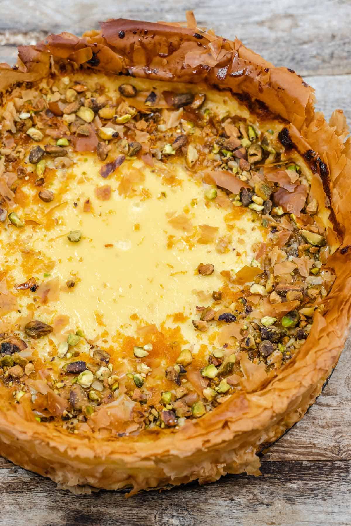 close up of a whole baklava cheesecake with nuts on top.