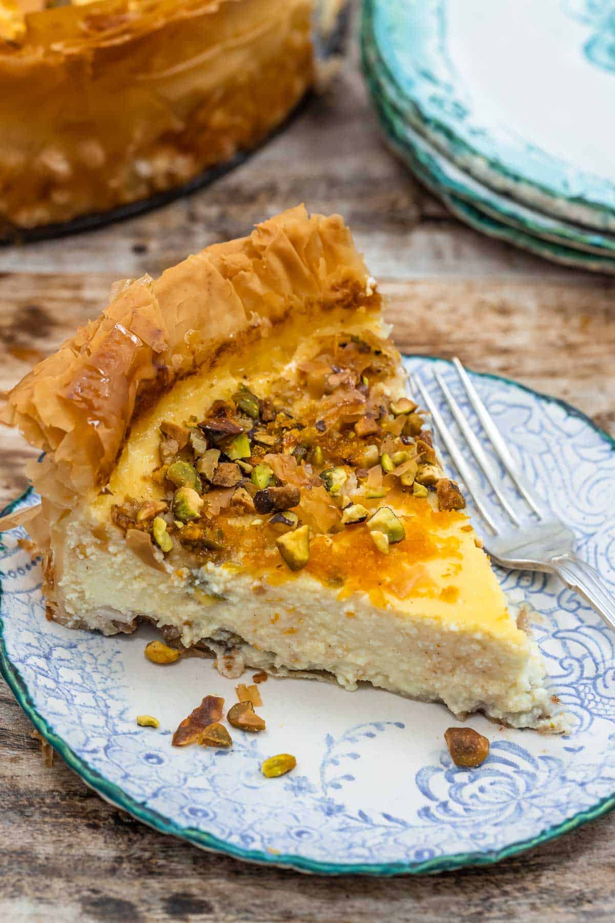 close up of a slice of baklava cheesecake on a plate with a fork.