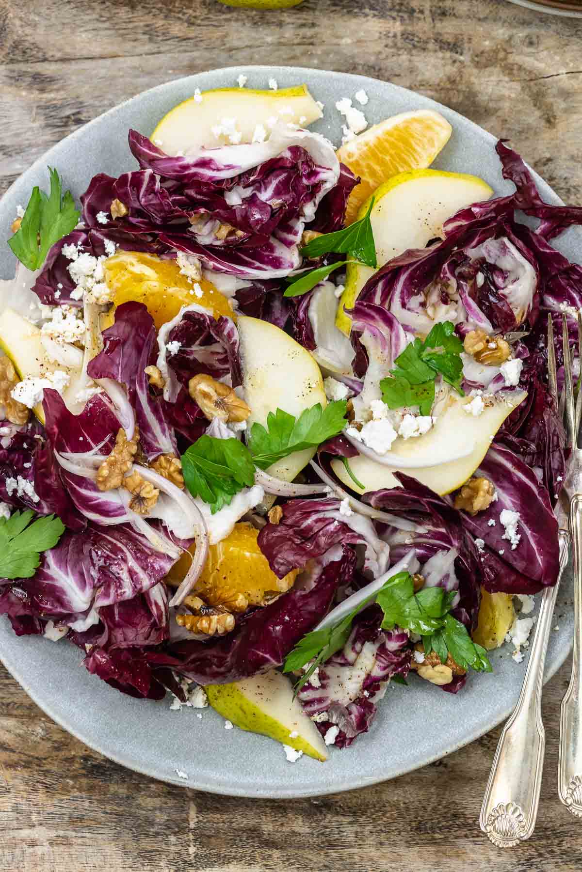 a plate of radicchio salad with pears, oranges shallots, walnuts and feta cheese.