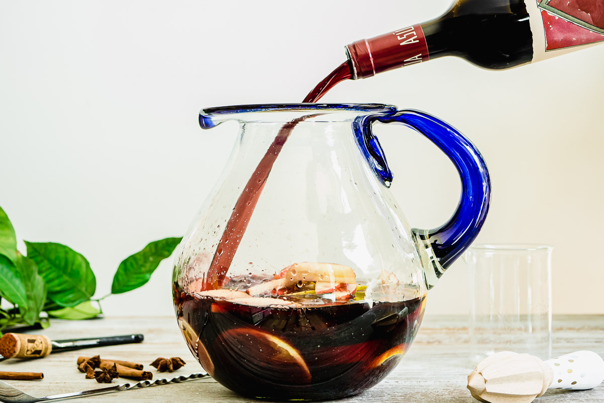 red wine being poured into a glass pitcher.