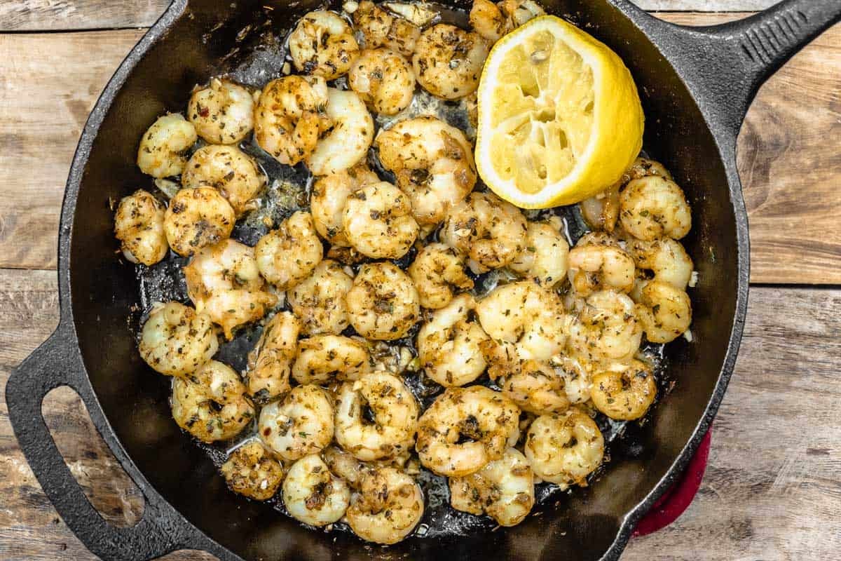 sautÃ©ed shrimp in s skillet with a half of a lemon.