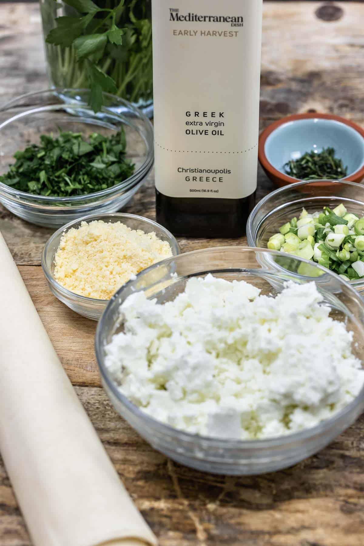 ingredients for sigara boregi including parsley, phyllo dough, parmesan cheese, feta cheese, scallions, thyme and olive oil.