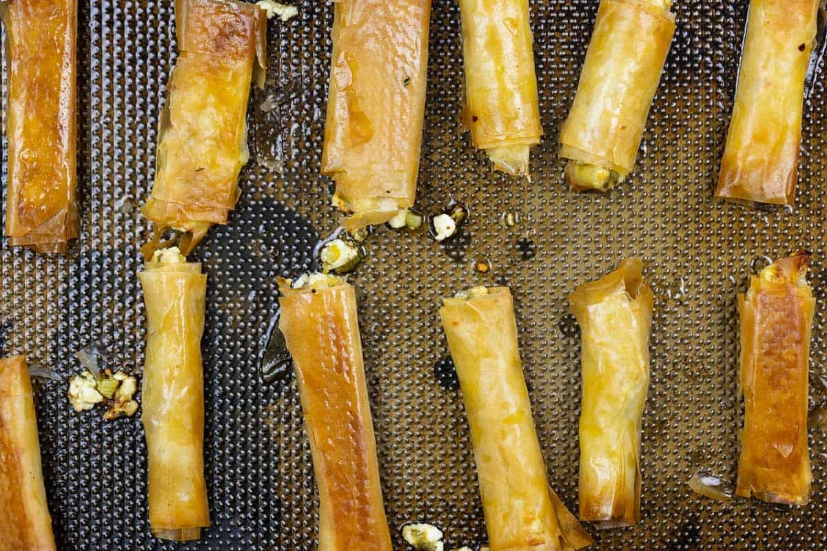 Twelve cooked sigara boregi rolls on a sheet pan.