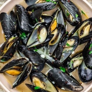 Steamed mussels with a garlicky broth in a small bowl.