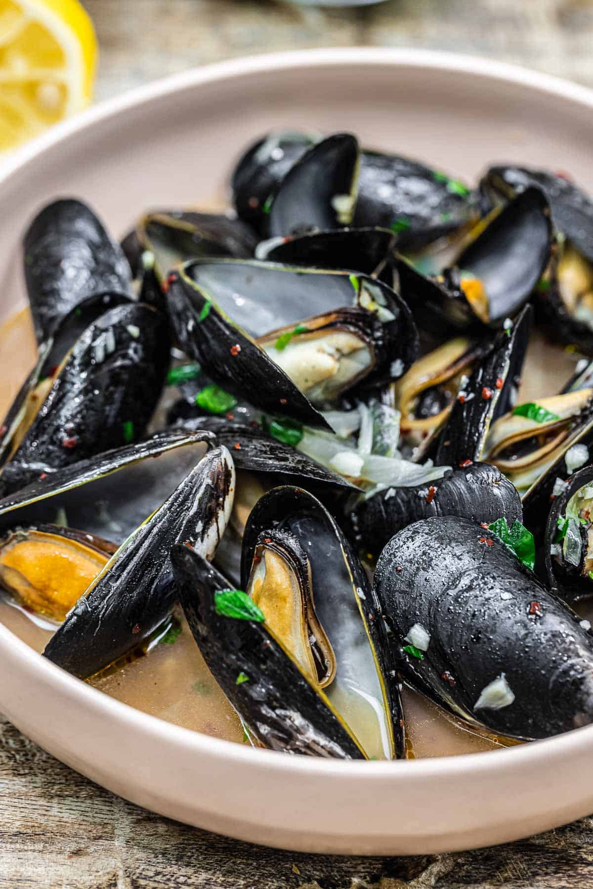 Close up of steamed mussels in a small bowl.