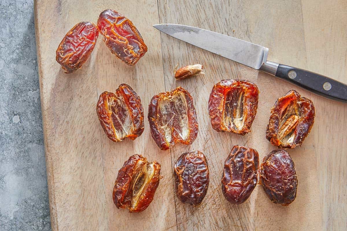 pitted dates on a cutting board with a knife.