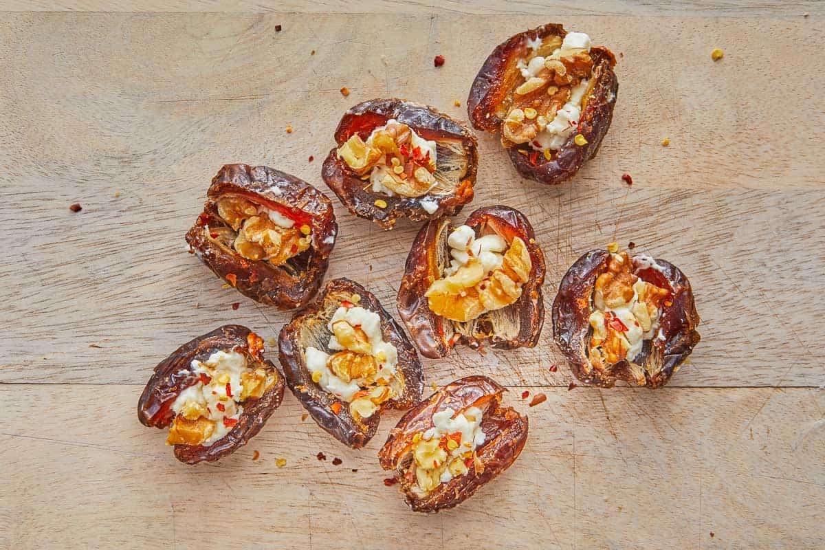 close up of cheese stuffed dates on a cutting board.