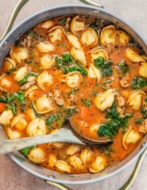 tortelllini soup in a dutch oven with a wooden spoon.