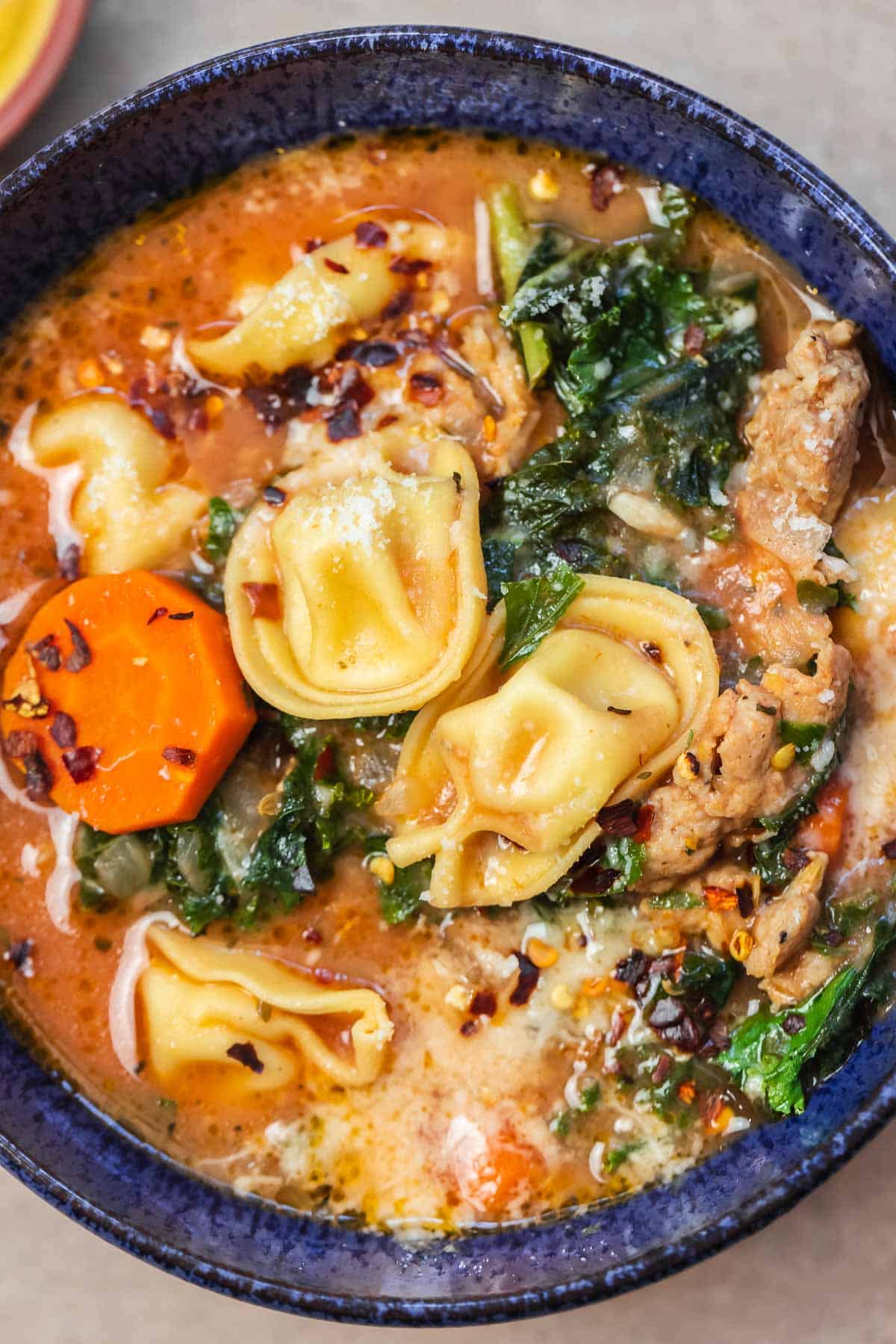 tortellini soup in a blue bowl.