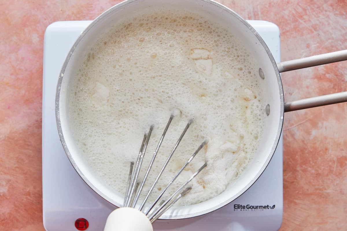 simple syrup and cornstarch being whisked together in a saucepan.