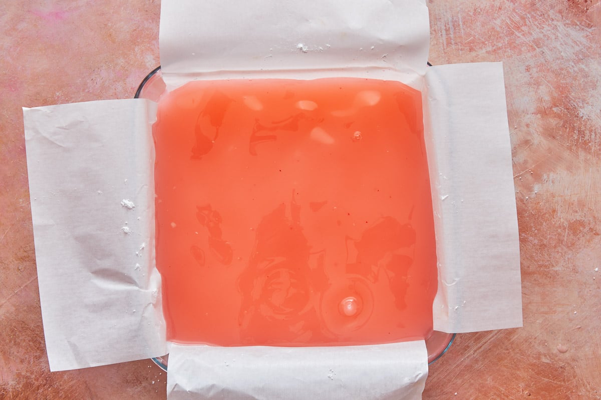 a large block of turkish delight being set in a glass dish lined with parchment paper.