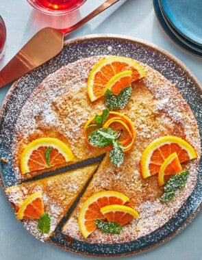 orange cardamom olive oil cake topped with orange slices on a plate with one slice cut.