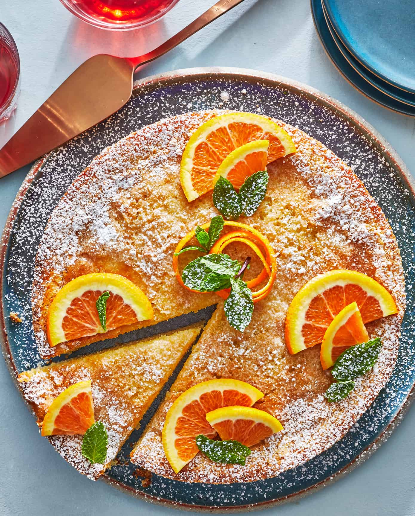 orange cardamom olive oil cake topped with orange slices on a plate with one slice cut.