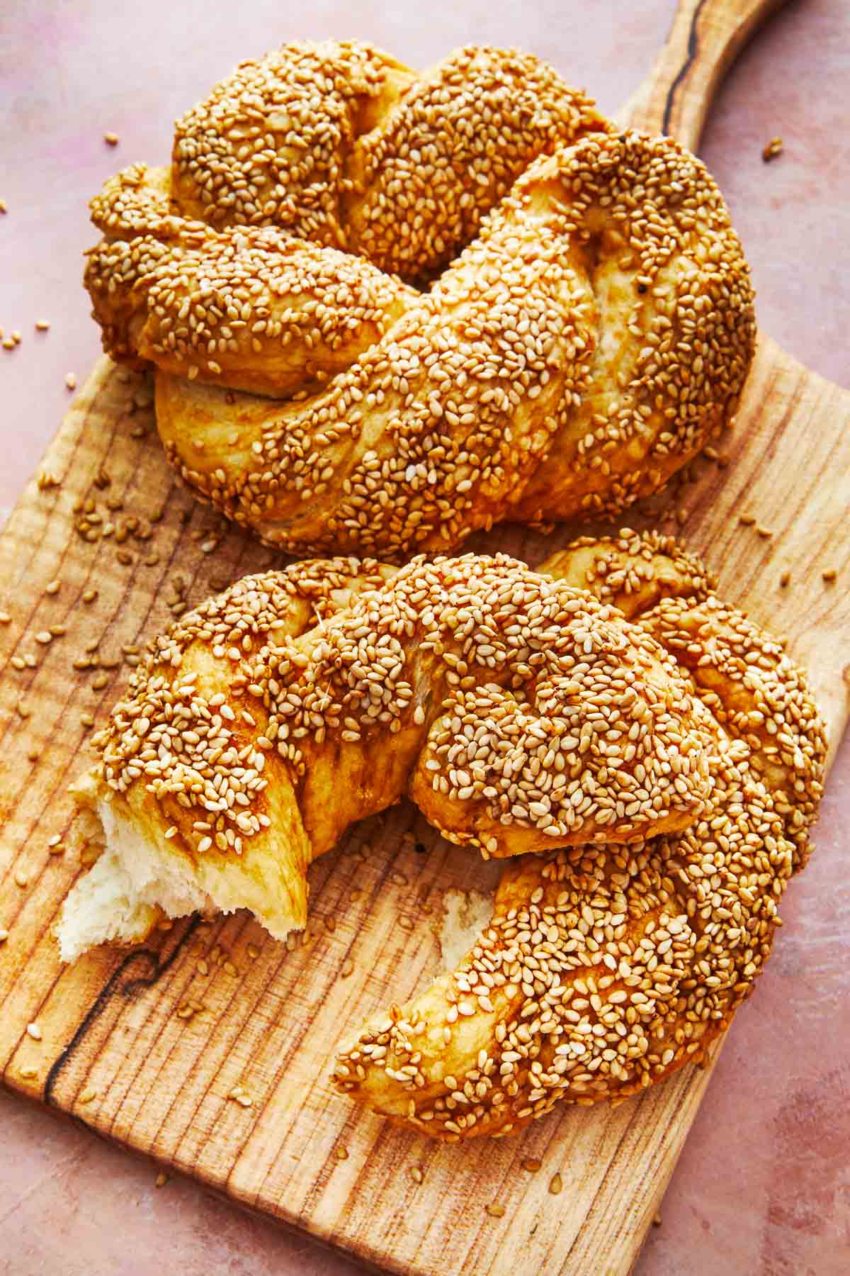 two baked simit rings on a cutting board.