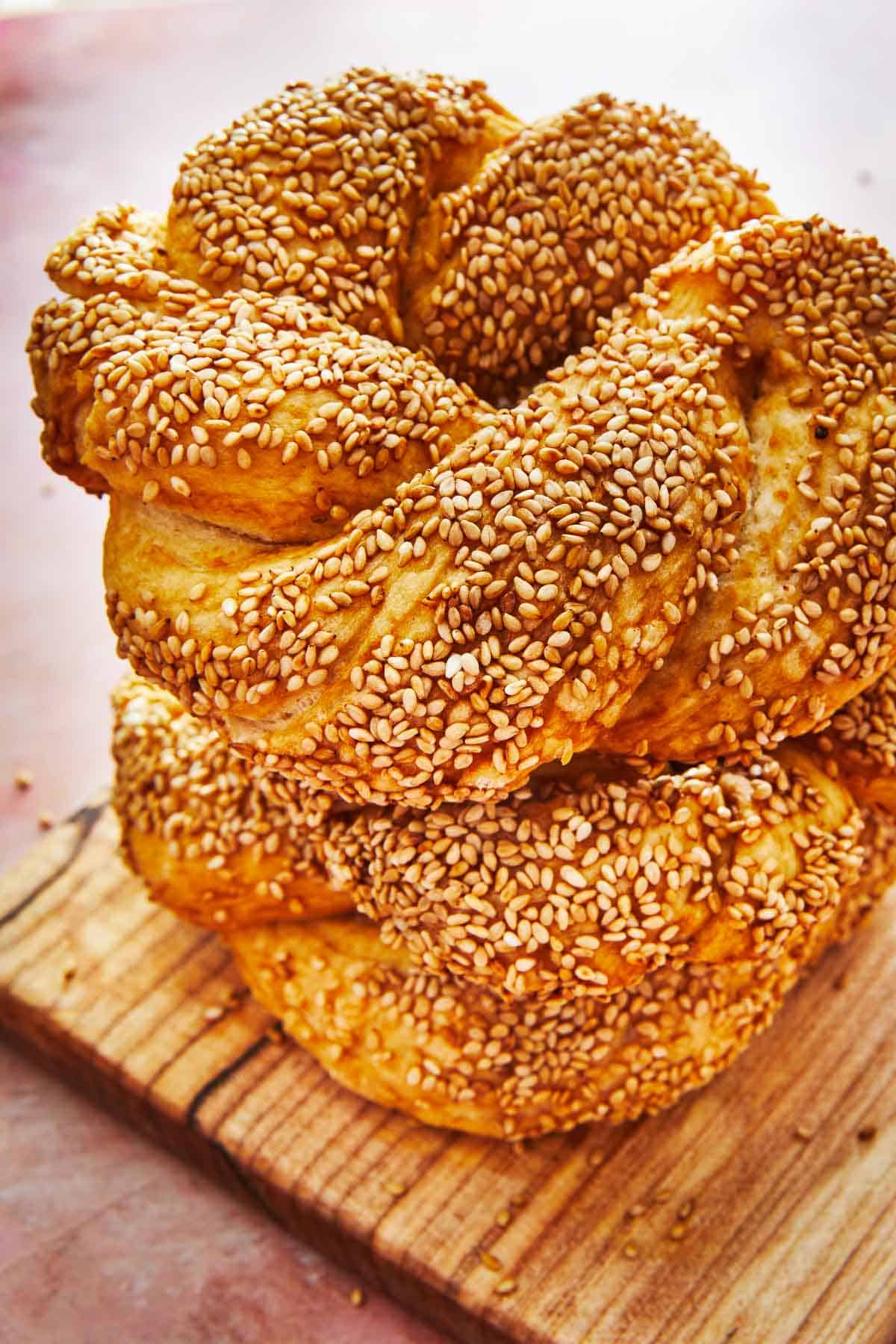 two baked simit rings stacked on top of each other on a cutting board.