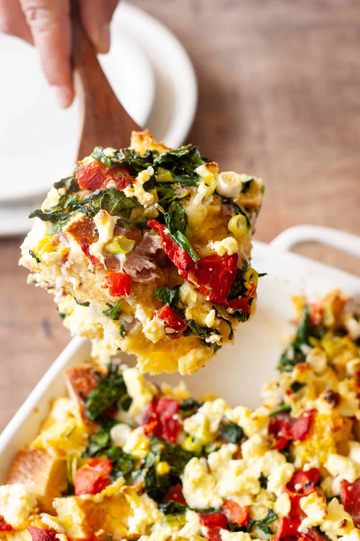 a slice of breakfast strata being taken out of a baking dish.