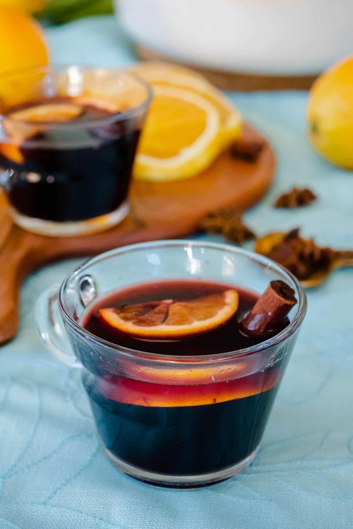 two cups of mulled wine with orange slices and cinnamon sticks.