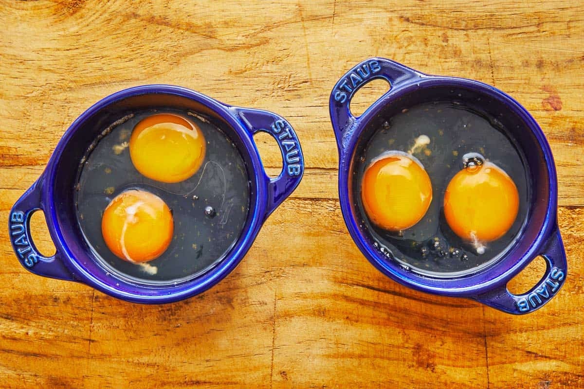 2 small baking dishes containing two raw eggs each.