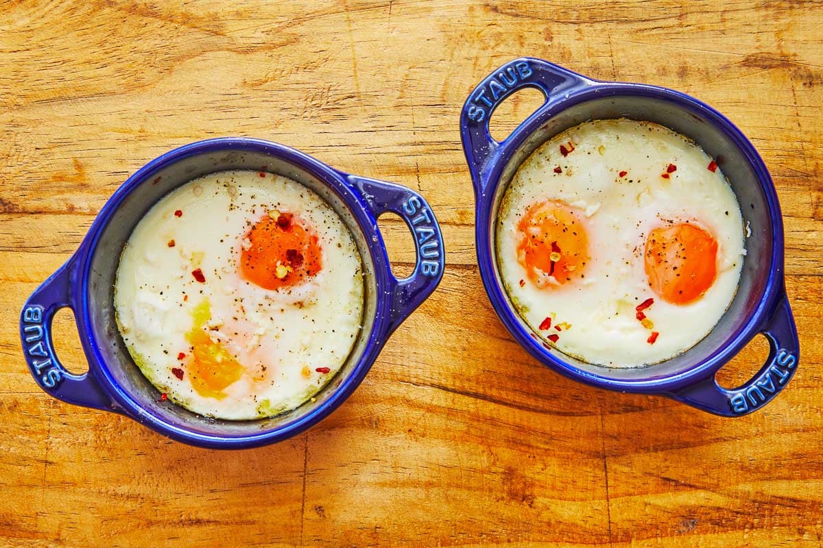 to small baking dished with two cooked baked eggs each.