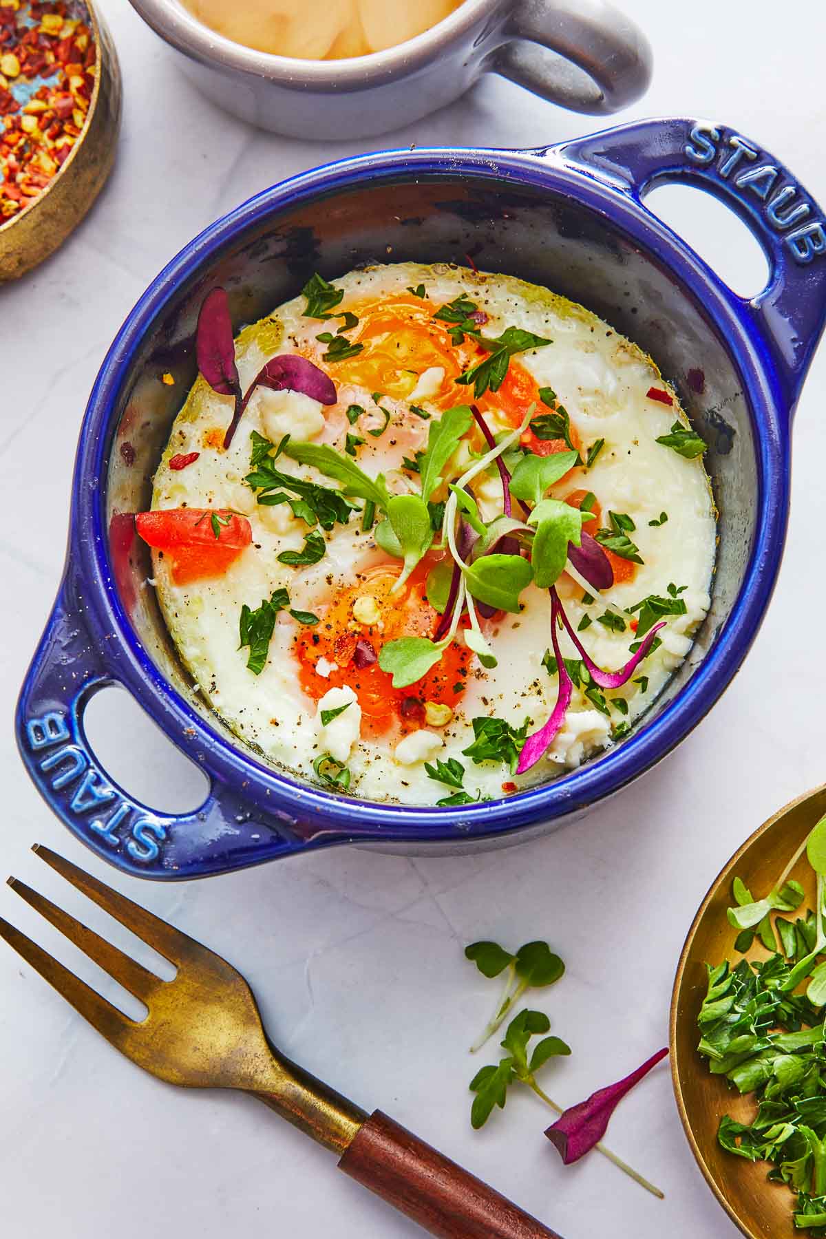 cooked baked eggs in a small baking dish next to a fork.