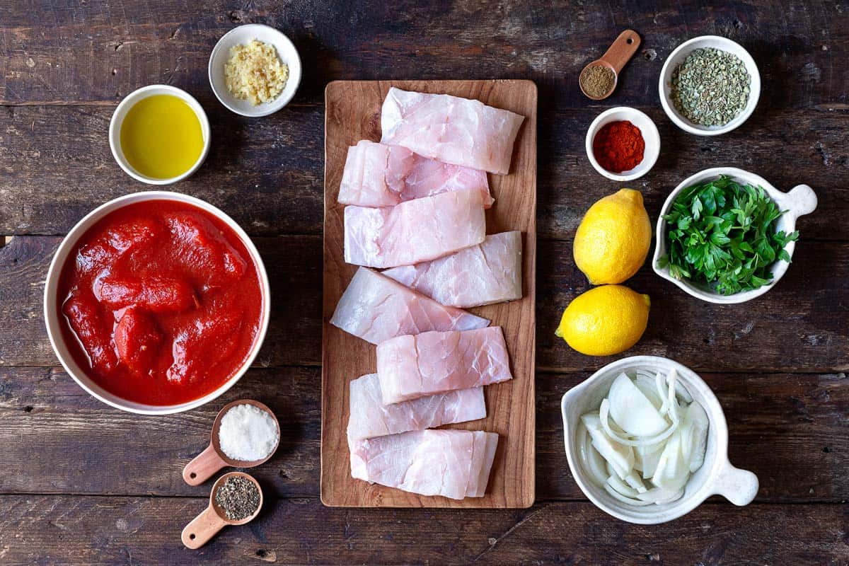 fish fillets, onions, canned whole tomatoes, lemon, and seasonings for Greek fish plaki recipe