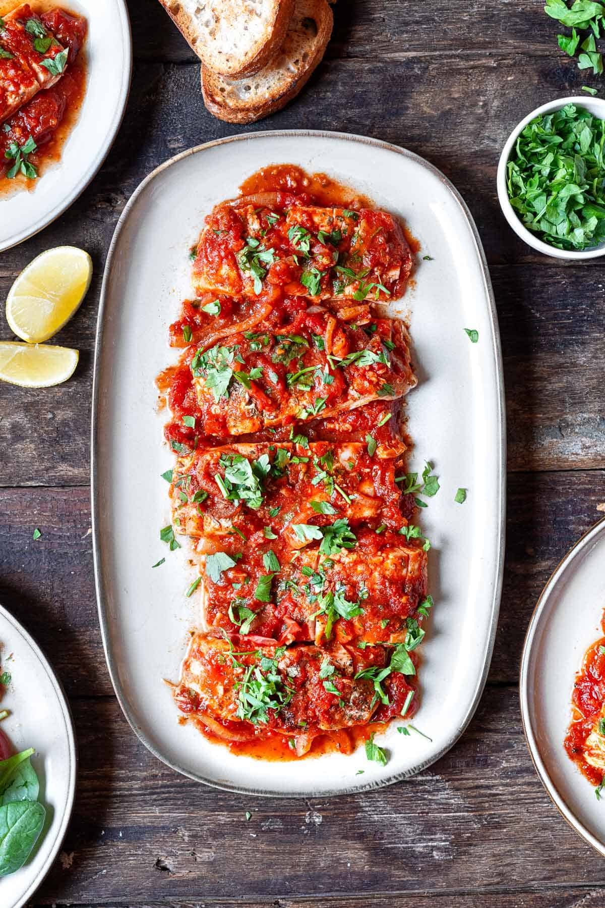 greek fish with onions and tomato on a serving platter.