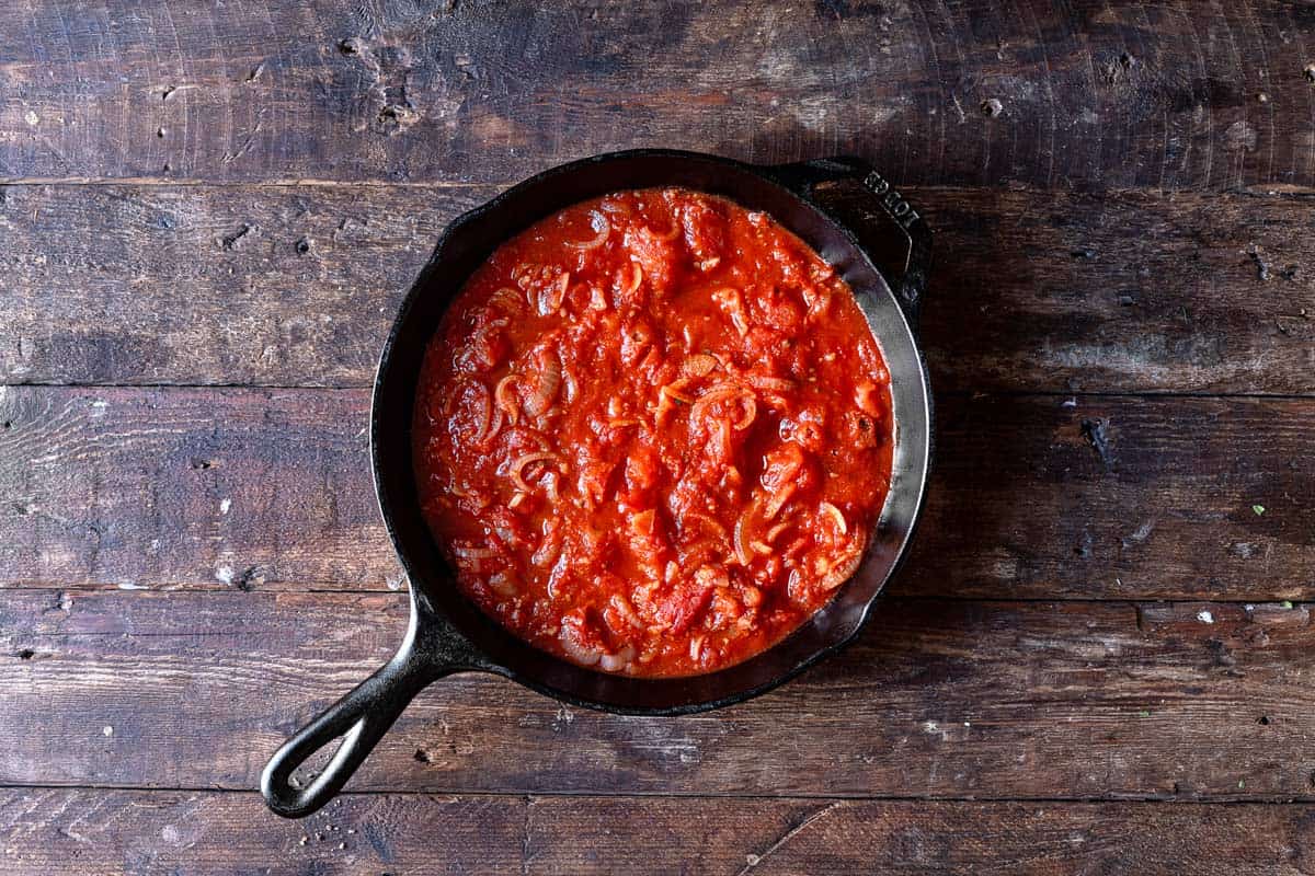 tomato sauce sautéing in a cast iron skillet.