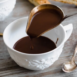italian hot chocolate (Cioccolato Caldo) being poured into a tea cup with a ladle.