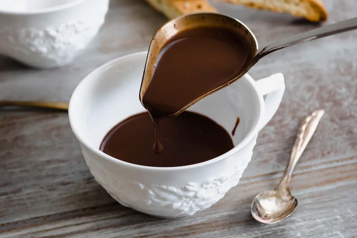 italian hot chocolate (Cioccolato Caldo) being poured into a tea cup with a ladle.