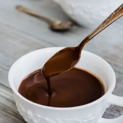 a mug of italian hot chocolate being stirred with a spoon.