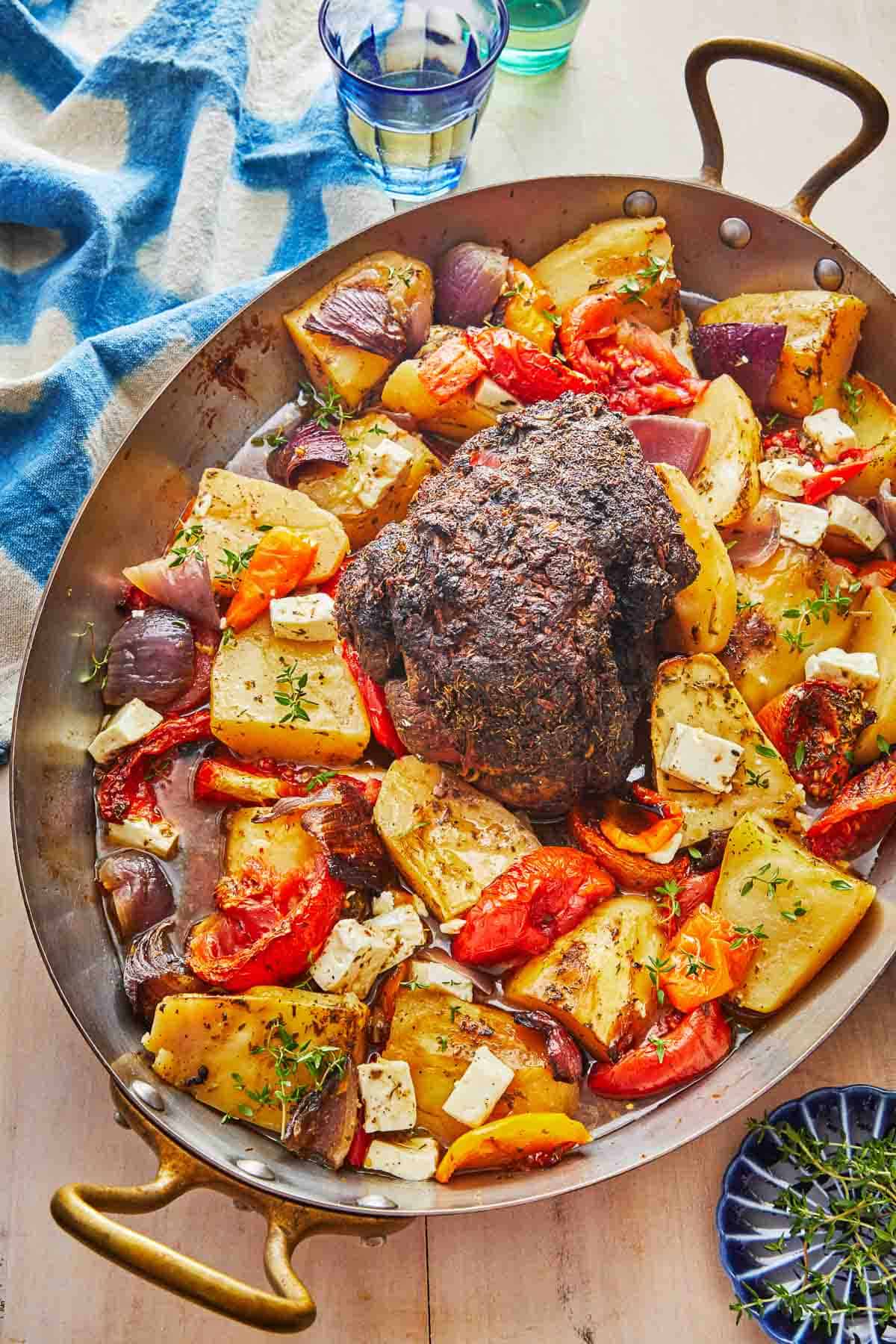 lamb kleftiko and vegetables in a roasting pan.