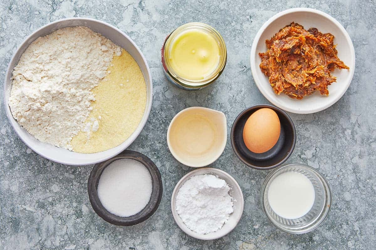 ingredients for ma'amoul including butter, granulated sugar, an egg, orange blossom water, semolina, flour, mahleb, milk, confectioners' sugar, and date paste.