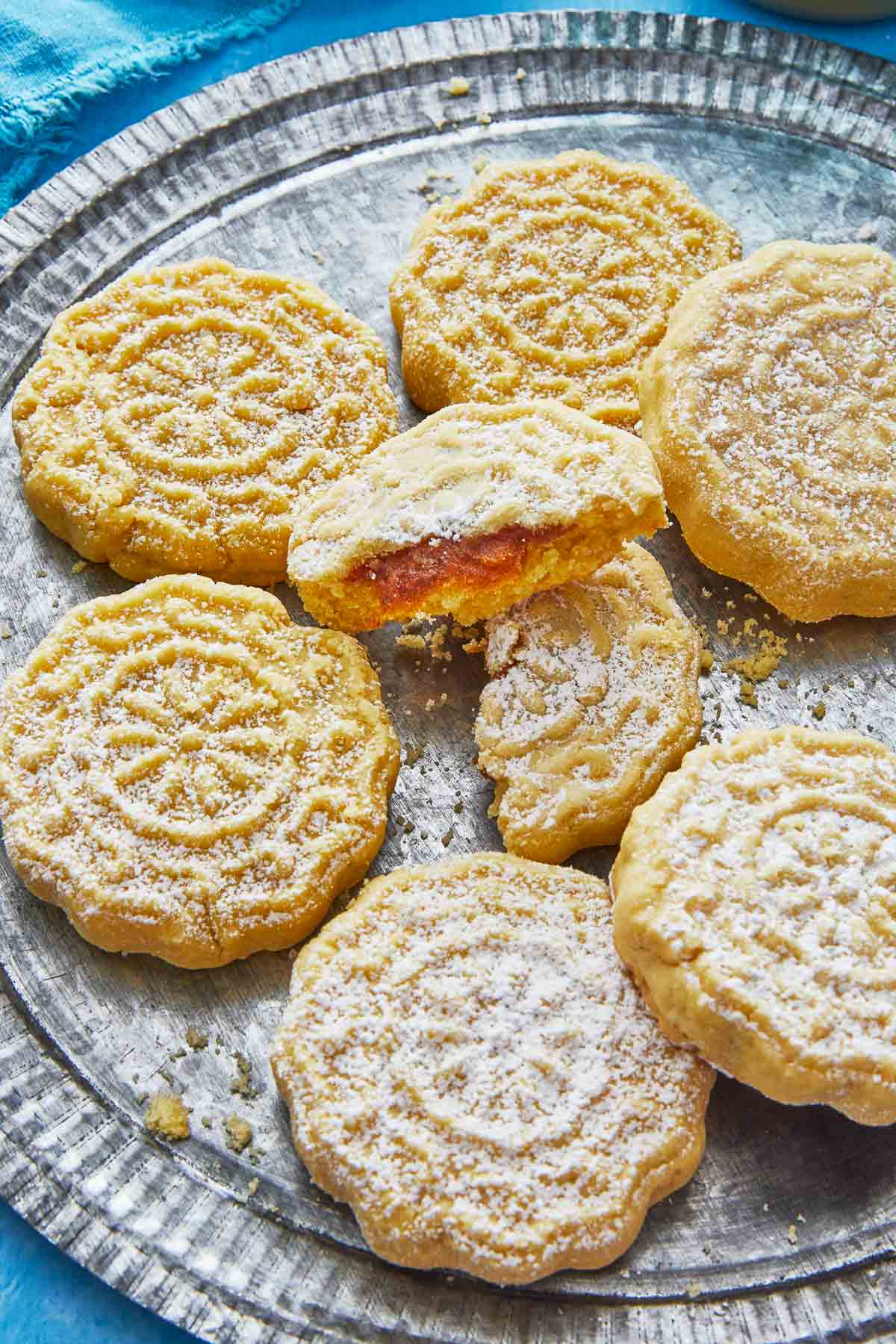 close up of six whole and one broken ma'amoul cookies on a plate.