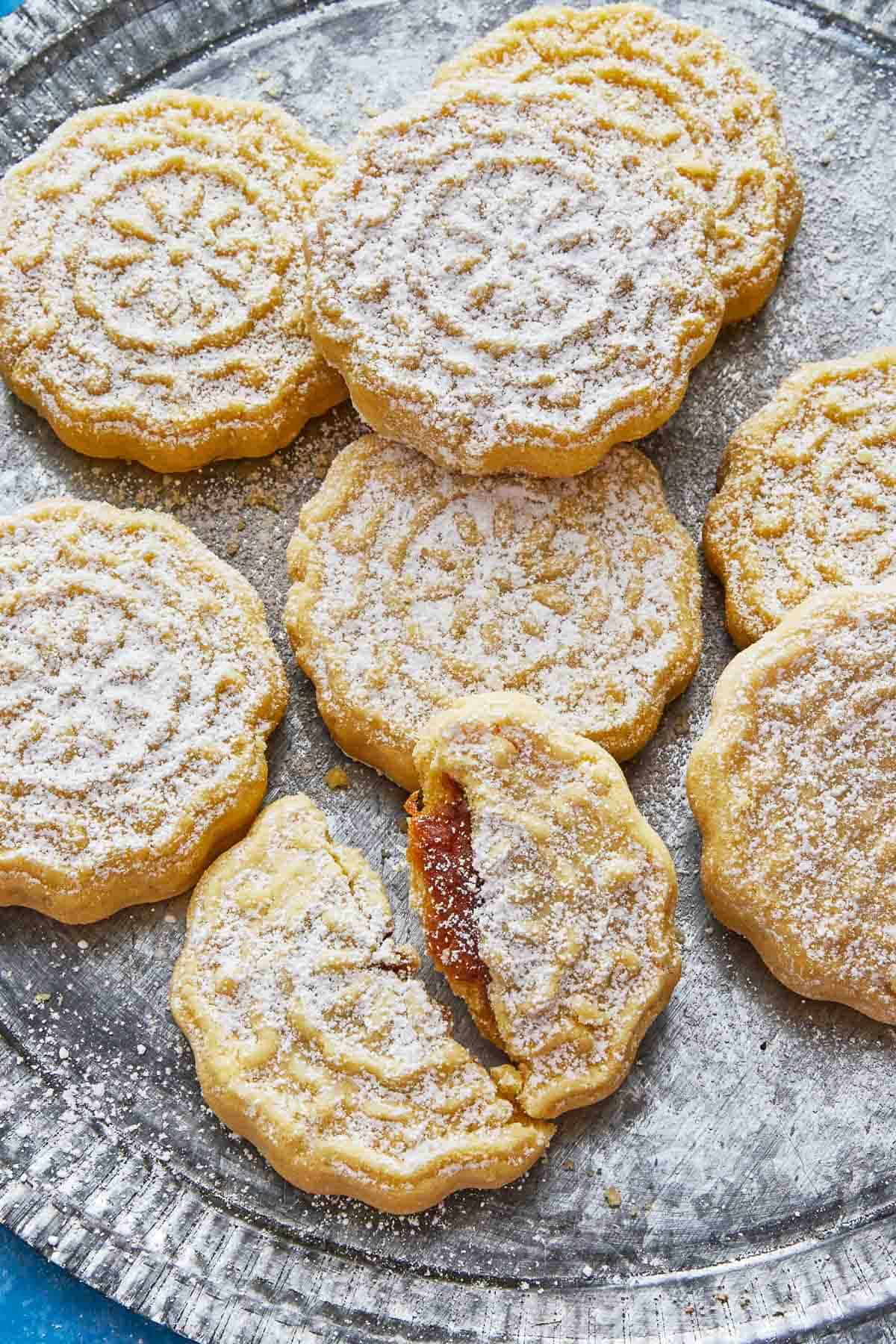 close up of six whole and one broken ma'amoul cookies on a plate.