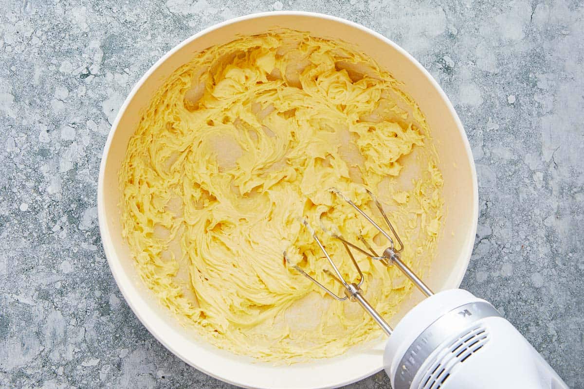 butter in a bowl being mixed with a hand mixer.