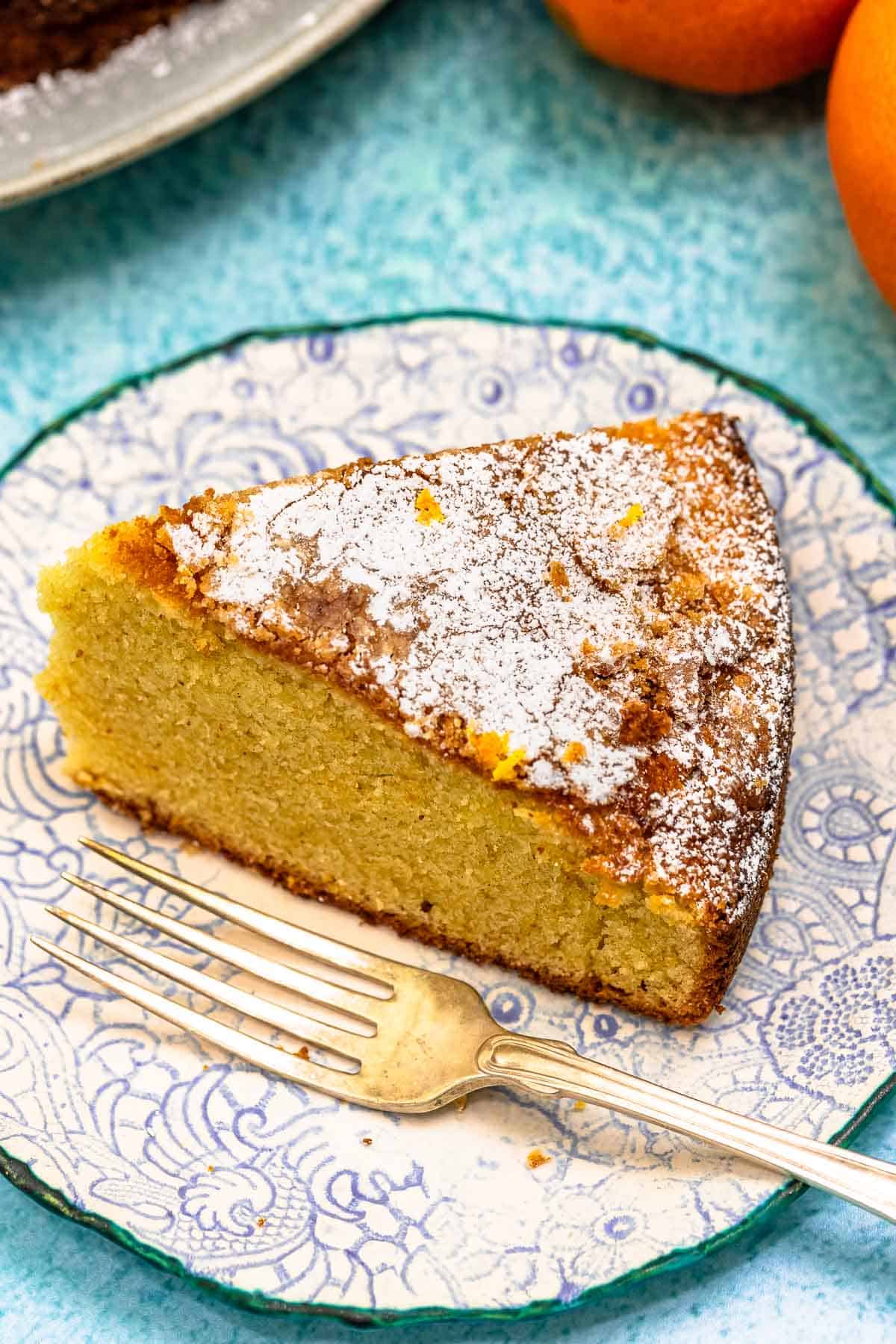 a slice of orange cardamom olive oil cake on a plate with a fork.