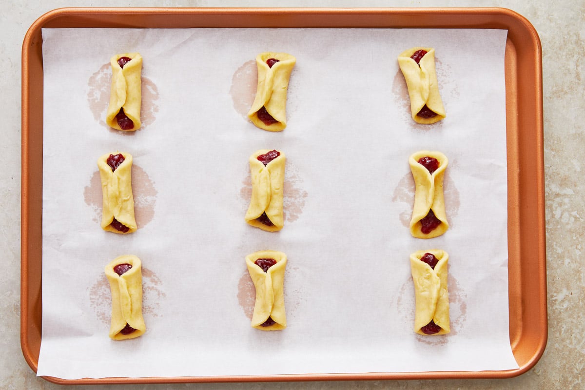 nine unbaked pizzicati cookies on a baking sheet lined with parchment paper.