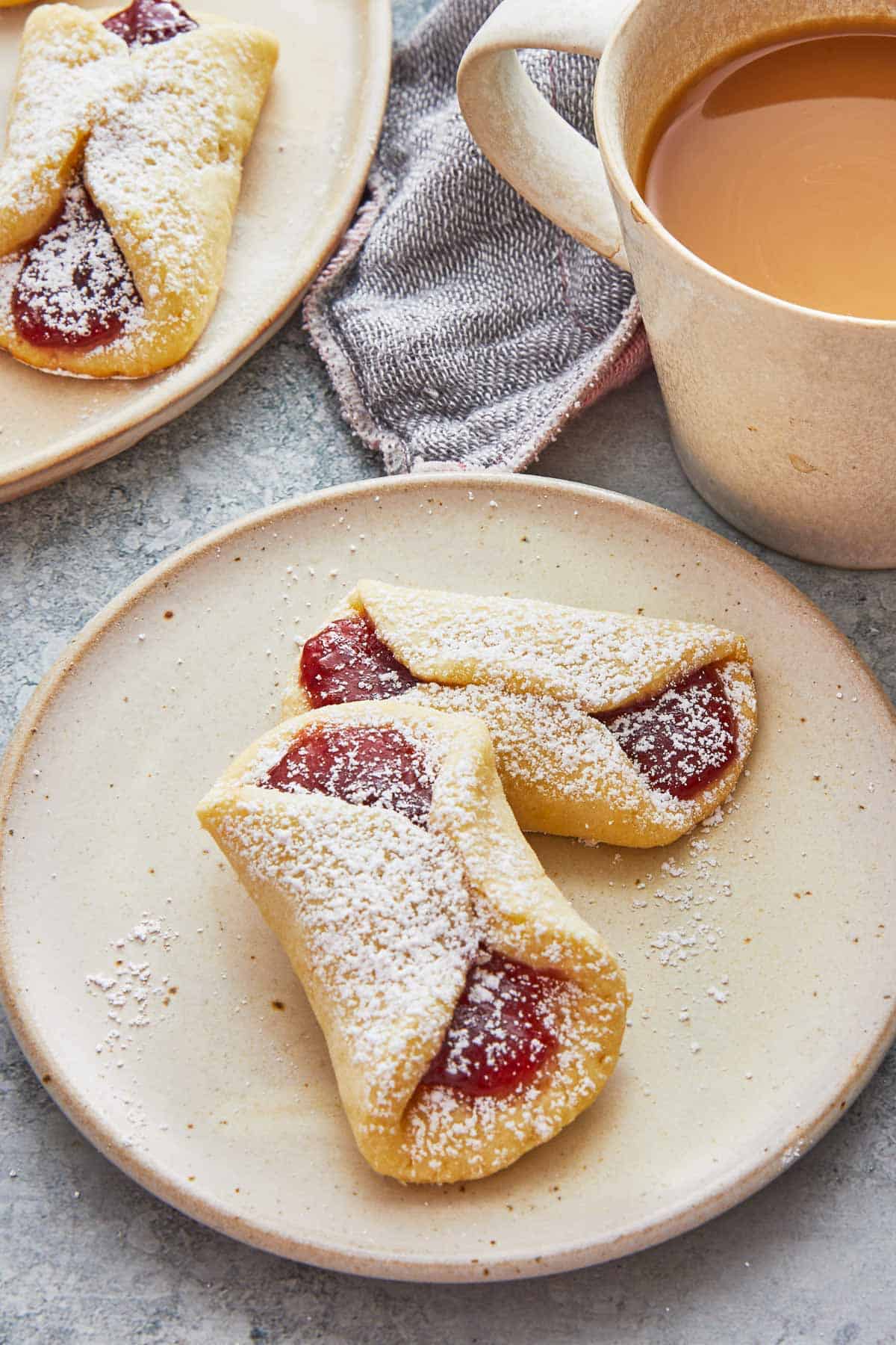 two pizzicati cookies on a plate with a cup of coffee.