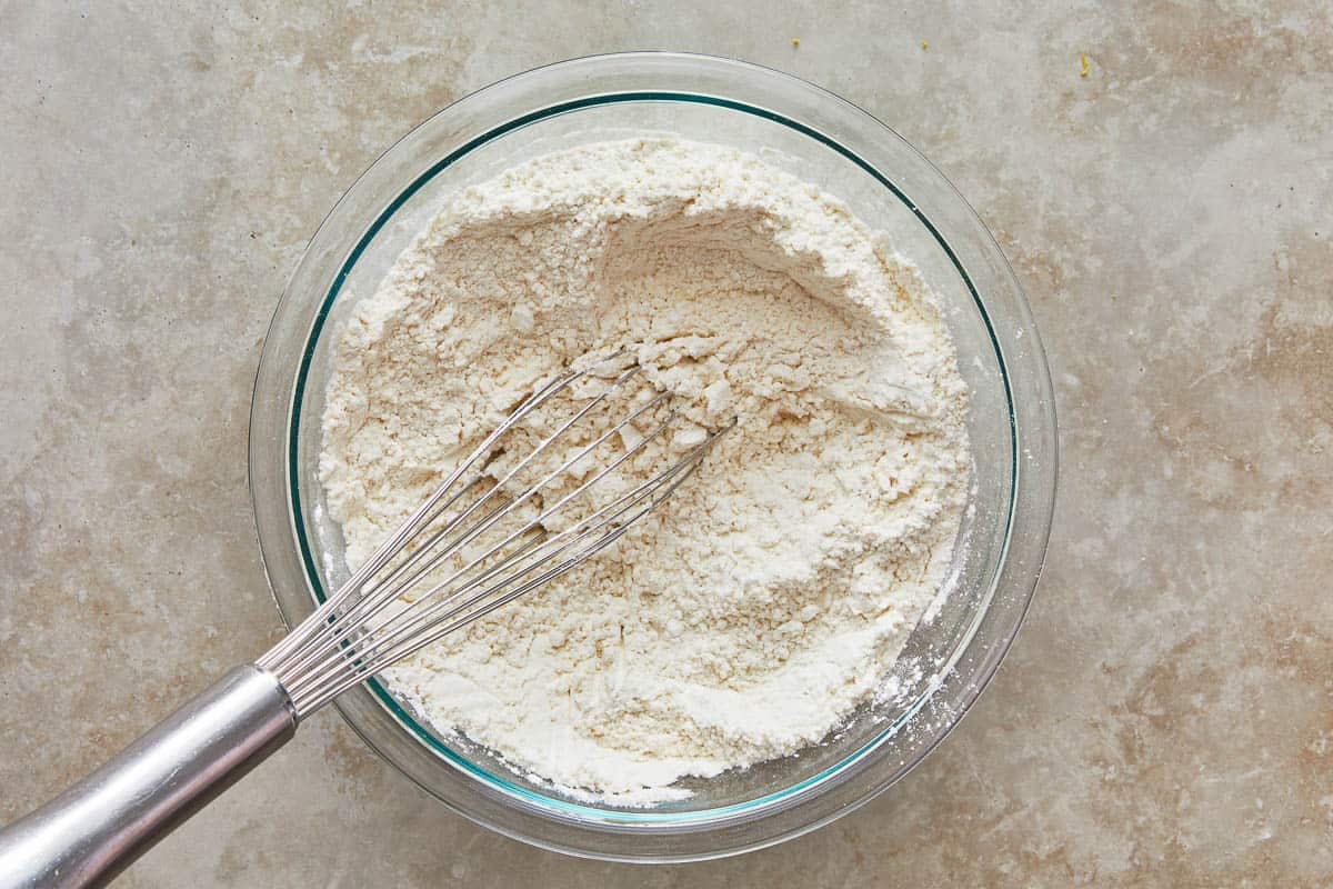 dry ingredients for pizzicati being mixed in a glass bowl with a whisk.