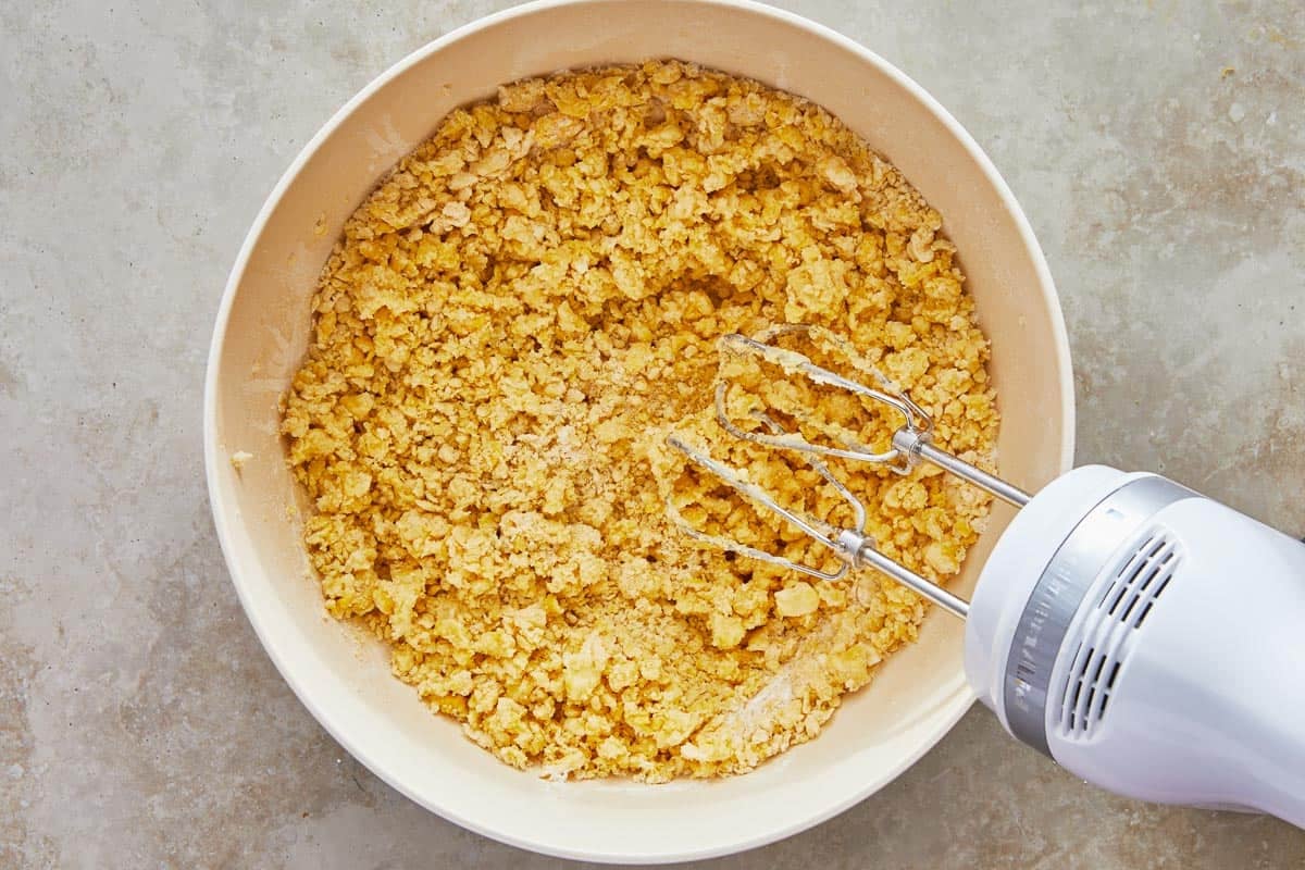 the pizzicati dough being mixed in a bowl with a hand mixer.