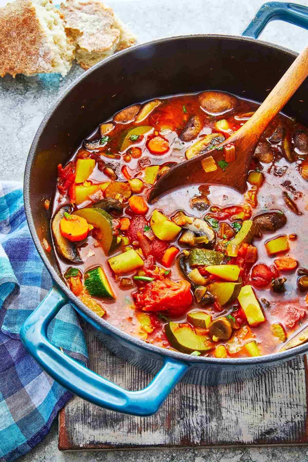 vegetable soup in a dutch oven with a wooden spoon.