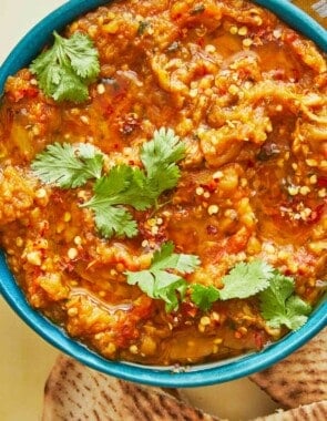 zaalouk (Moroccan cooked eggplant salad) in a blue bowl with a cilantro garnish.