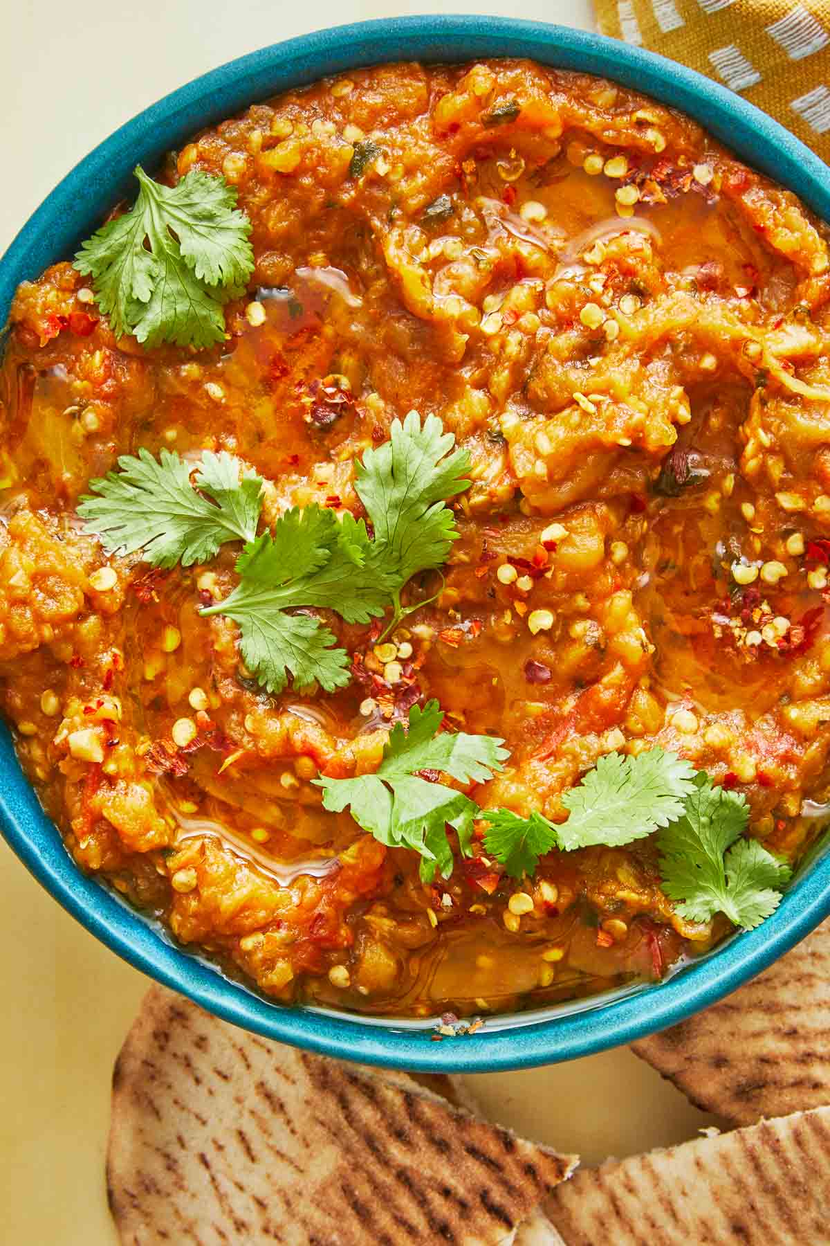 zaalouk (Moroccan cooked eggplant salad) in a blue bowl with a cilantro garnish