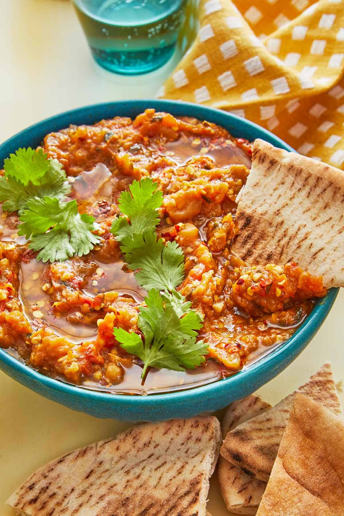 a triangle of pita bread being dipped into a bowl of zaalouk (Moroccan cooked eggplant salad).